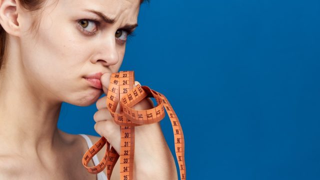 A woman with a measuring tape in her hands.