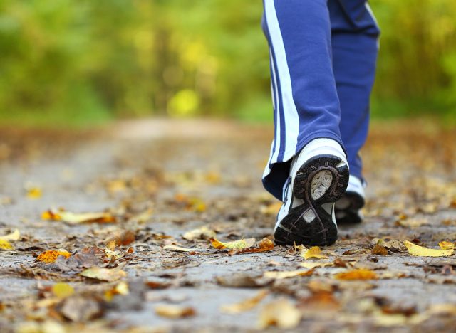 Woman walking cross country and trail in autumn forest