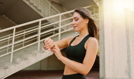 Attractive sport woman in sportswear use smart watch outdoors at urban environment
