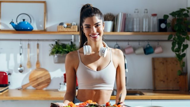 Shot of fintess woman making a healthy poke bowl in the kitchen at home.