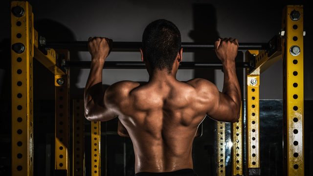 Rear view of healthy muscular young man with his arms stretched out, Strong athletic man fitness model torso showing six pack abs, Muscular athletic bodybuilder fitness model