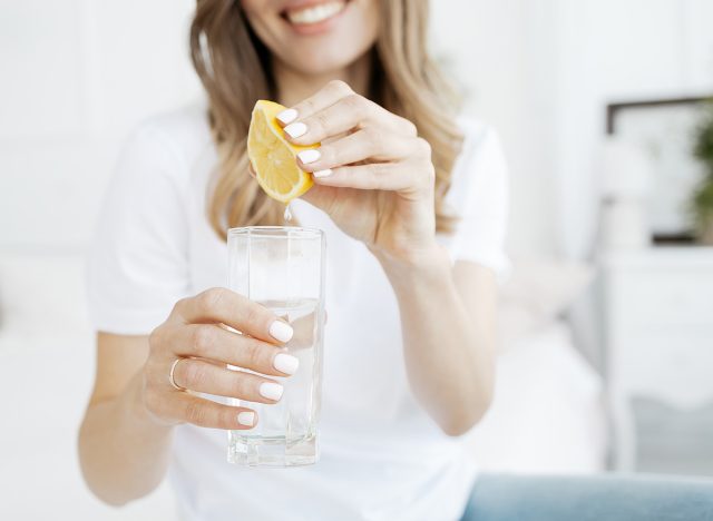 Woman squeezes lemon juice into a glass.