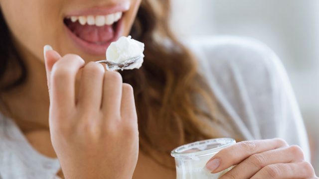 Close-up of woman's hand holding yogurt while eating at home.