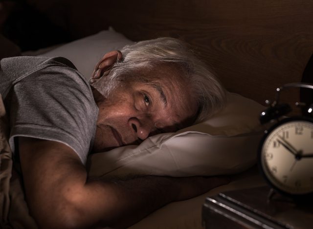 Depressed senior man lying in bed cannot sleep from insomnia