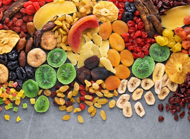 Dried fruits and berries on gray background top view. Lemons, oranges, bananas, raisins, cranberries, kiwi, cherries, ginger, plums, strawberries, dried apricots, tangerines, dates, pineapples, figs,
