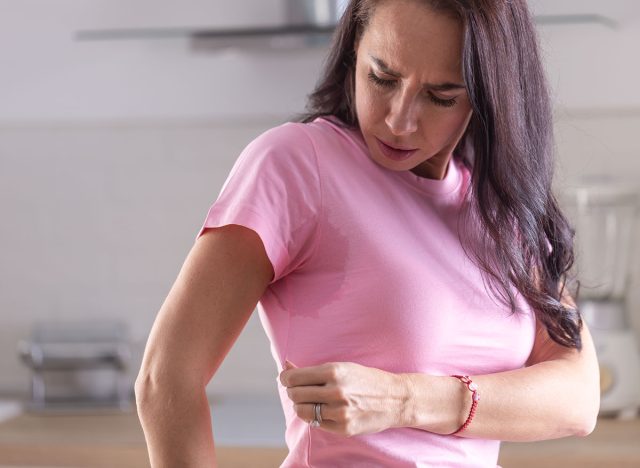 Excessive sweating visible by stains on a pink shirt of a young woman.