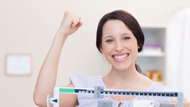 Smiling young woman happy about what the scale shows