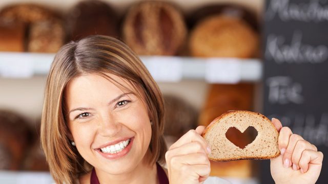 Happy woman showing bread with heart shape