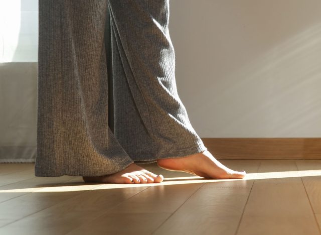 Barefoot woman on the wooden floor. Concept of the underfloor heating in the apartment.
