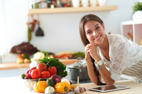 Young woman using a tablet computer to cook in her kitchen