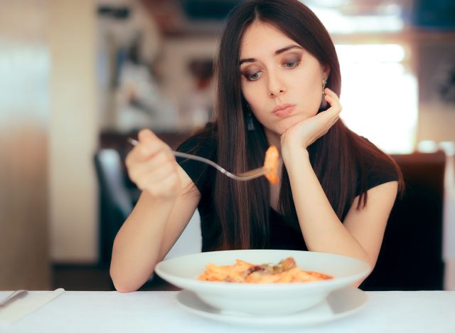 Female Customer Unhappy with the Dish Course in Restaurant. Depressed lonely woman suffering from appetite loss