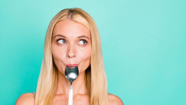 Close-up portrait of nice attractive lovely sweet girlish funny feminine funky cheerful straight-haired girl licking silver spoon lunch dinner isolated on bright vivid shine green turquoise background