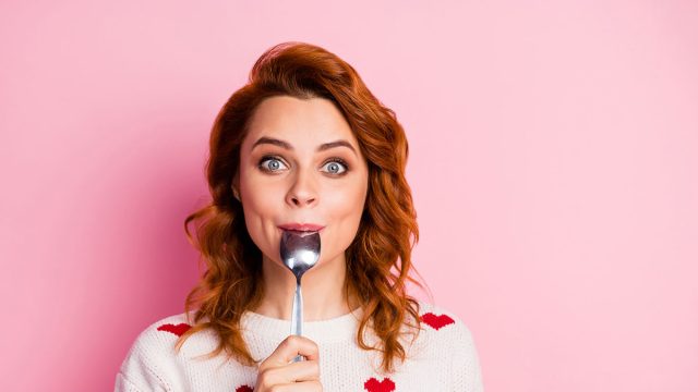 Close-up portrait of her she nice attractive pretty cute glad cheerful cheery wavy-haired girl licking spoon celebratory festal lunch homemade breakfast isolated on pink pastel color background