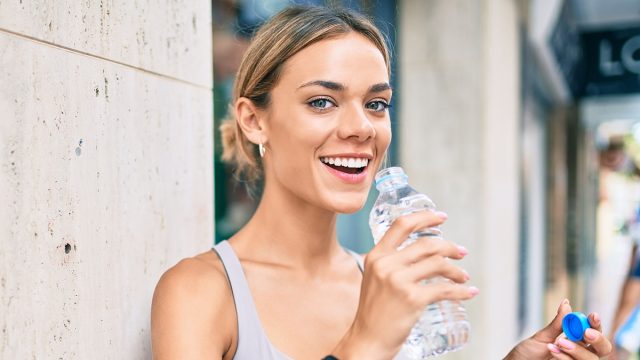 Young cauciasian fitness woman wearing sport clothes training outdoors drinking fresh water