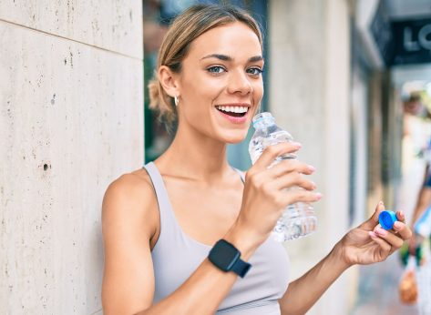 Young cauciasian fitness woman wearing sport clothes training outdoors drinking fresh water