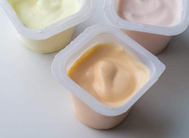 Flavoured yogurt in plastic pots - colourful fruit flavoured yogurt cups isolated on white with copy space - top view photo