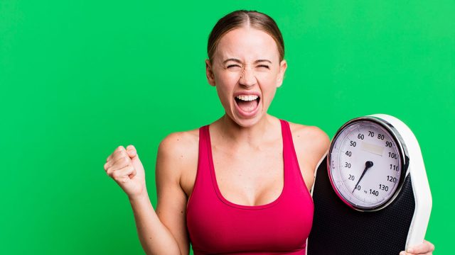 caucasian pretty woman shouting aggressively with an angry expression. fitness and diet concept