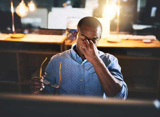 Black man in business, night and headache with stress and vision problem, crisis and burnout from overtime. Professional male with migraine, brain fog and work late with loss of focus and overworked