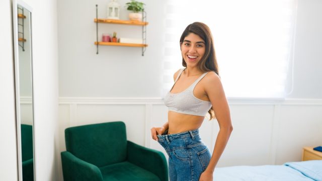 Portrait of an attractive hispanic woman wearing a size too big jeans.