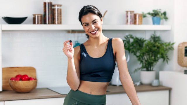 Shot of athletic woman eating a healthy bowl of muesli with fruit in the kitchen at home