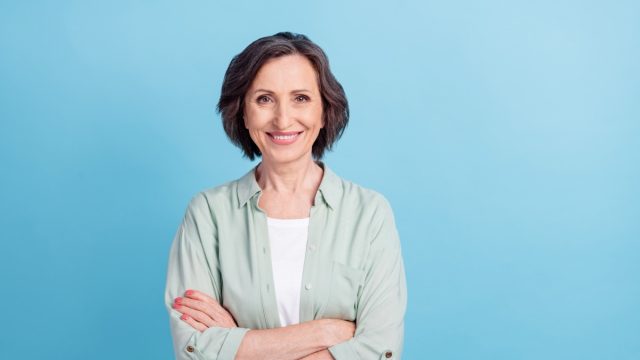 Photo portrait senior woman smiling happy folded hands in casual shirt isolated pastel blue color background.