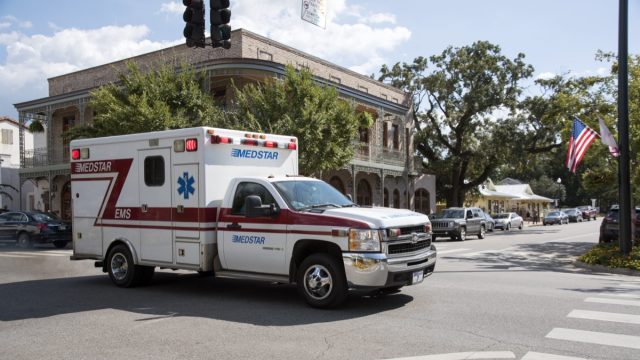 An ambulance on an emergency call driving through the town center of Fairhope.