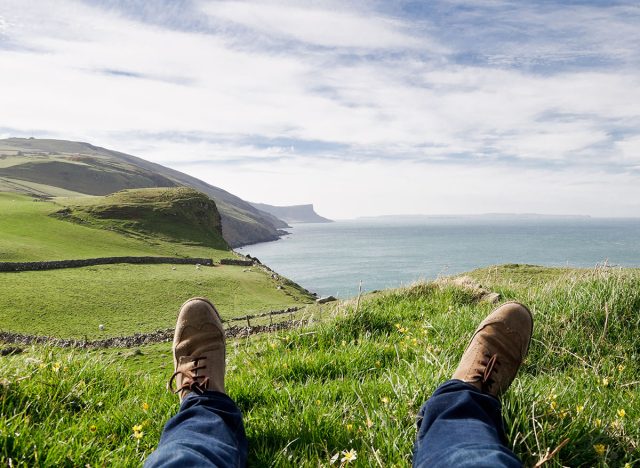 Man laying on the ground in a grass field, resting on a hill in the County Antrim, Northern Ireland