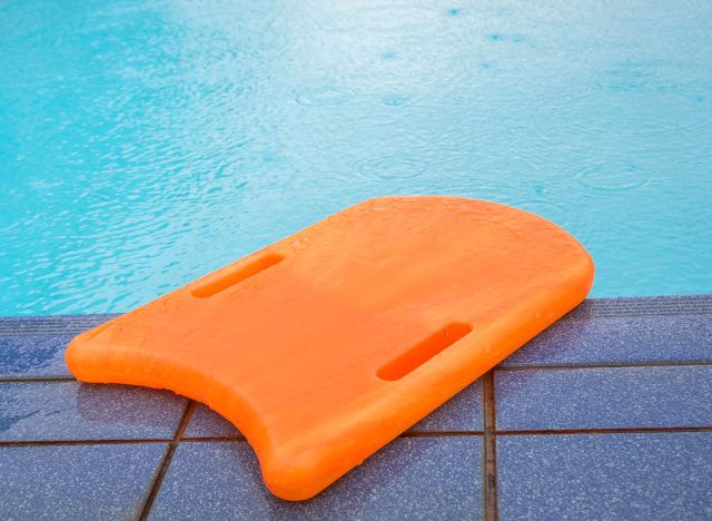 Orange kickboard beside the swimming pool, flutter board.