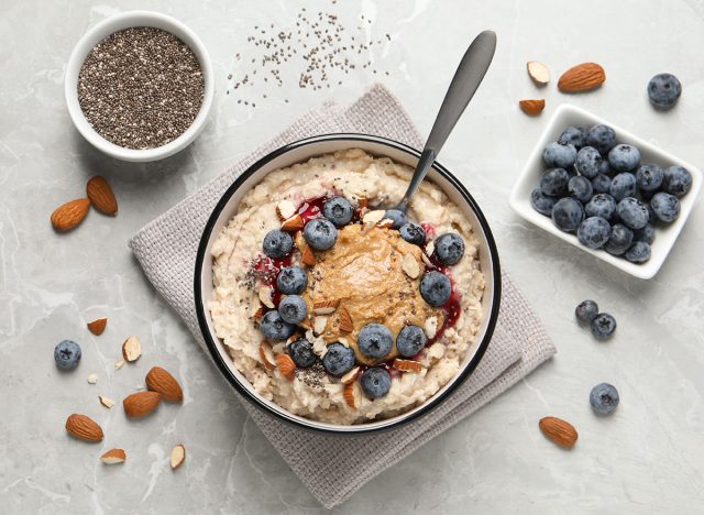 Tasty oatmeal porridge with toppings served on light grey table, flat lay