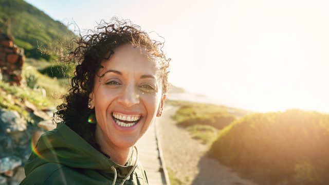 Portrait, morning and walk with woman, smile and fitness with sunshine, workout and nature. Face, person and runner with healthy routine, lens flare and vacation with exercise, warm up and training