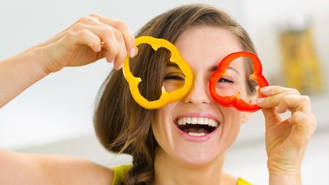 Funny young woman showing slices of bell pepper
