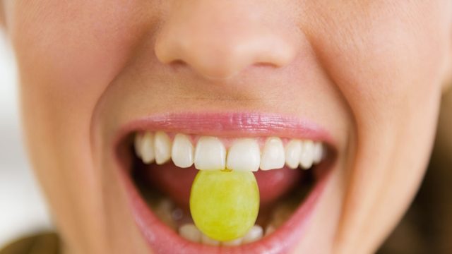 Closeup,On,Young,Woman,Holding,Grape,In,Mouth
