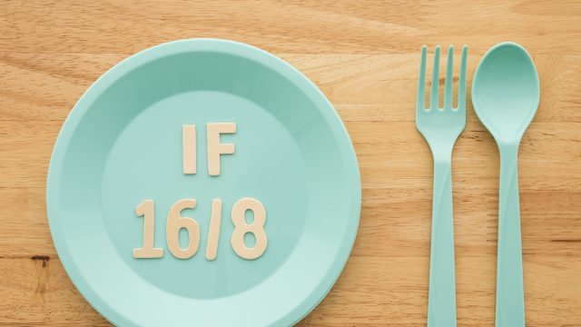 IF (Intermittent Fasting) 16 and 8 diet rule and weight loss concept. Flat lay IF 16 and 8 letter on blue plate, spoon and fork on wooden table background.