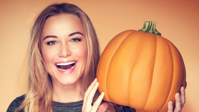 Portrait,Of,Beautiful,Cheerful,Woman,With,Pumpkin,Over,Orange,Background,