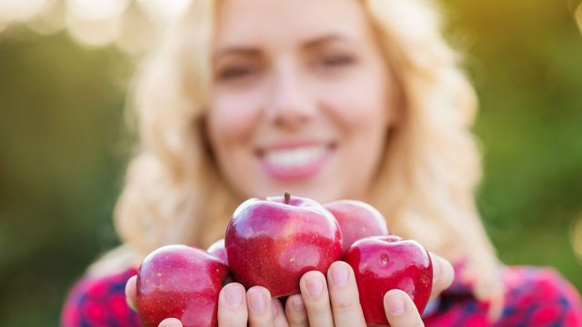 Beautiful woman harvesting apples, eating them