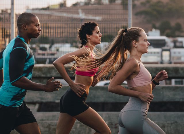Group of runners in fitness clothing running in the city. Young men and women running together in morning.