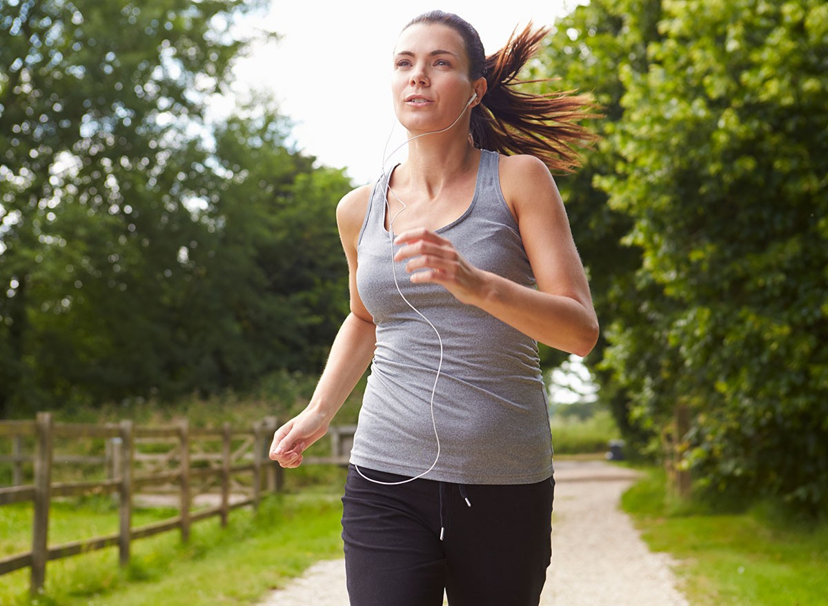 Woman Running In Countryside Wearing Earphones