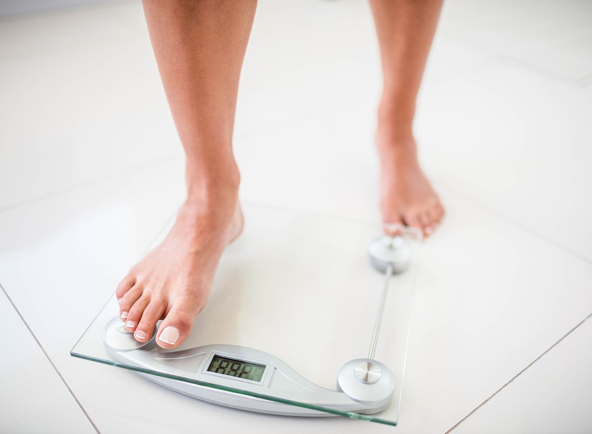 Womans feet going on weighting scale at home