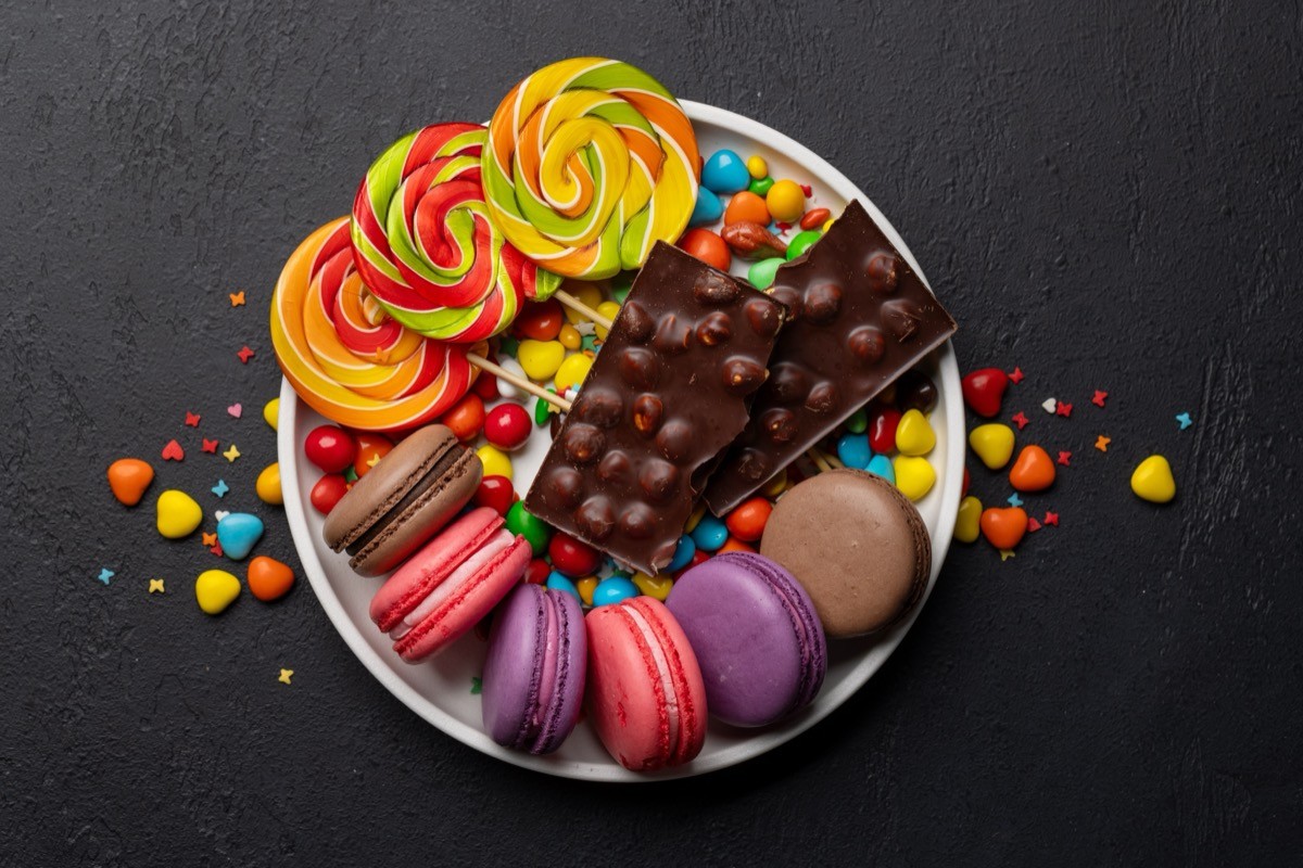 Various,Colorful,Candies,,Lollipops,,And,Macaroons.,Flat,Lay,Over,Stone