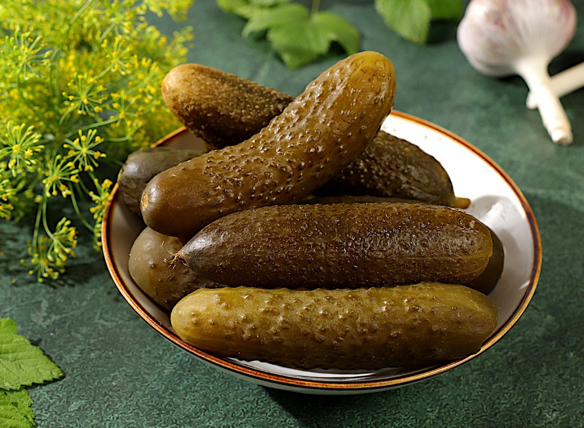 Fresh pickled cucumbers in a bowl with garlic and dill on a concrete table, village harvest, homemade pickling recipe, cucumbers and ingredients for pickling, home canning concept,
