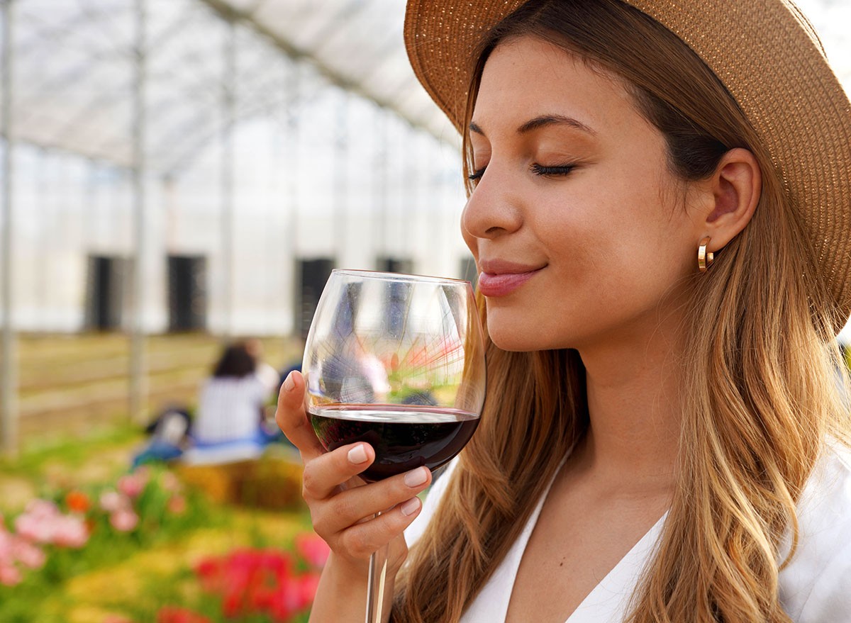 Close-up of beautiful woman smelling red wine from glass with closed eyes, Pino Noir