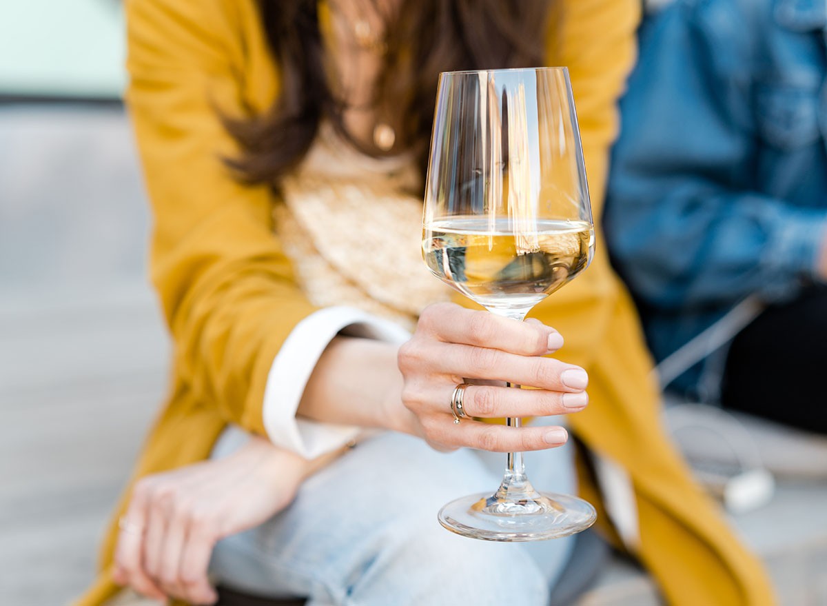 Stylish female holding glass with white wine
