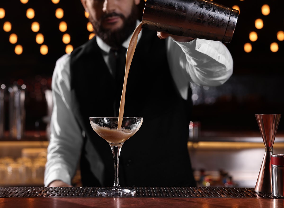 Bartender preparing Espresso Martini at bar counter, closeup. Alcohol cocktail