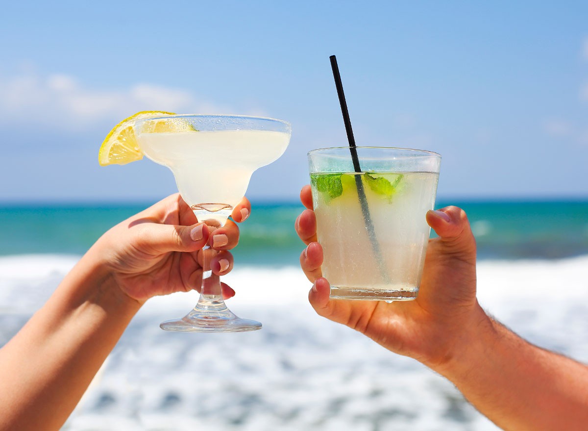 Two cocktail glasses in man and woman hands. Margarita and mojito cocktail