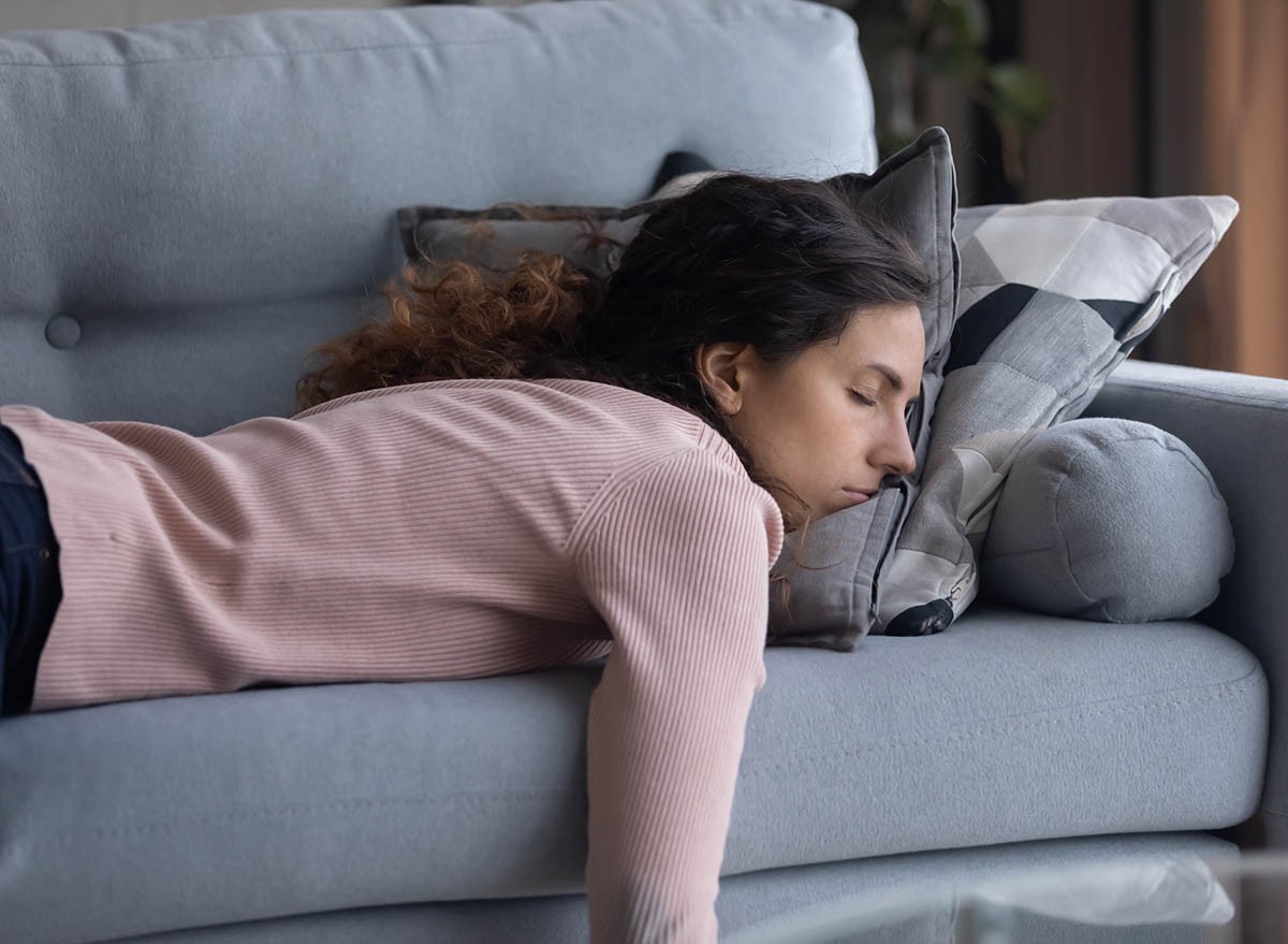 Exhausted young Caucasian woman lying on comfortable sofa in living room sleeping after hard-working day, tired millennial female fall asleep on couch at home, take nap or daydream, fatigue concept