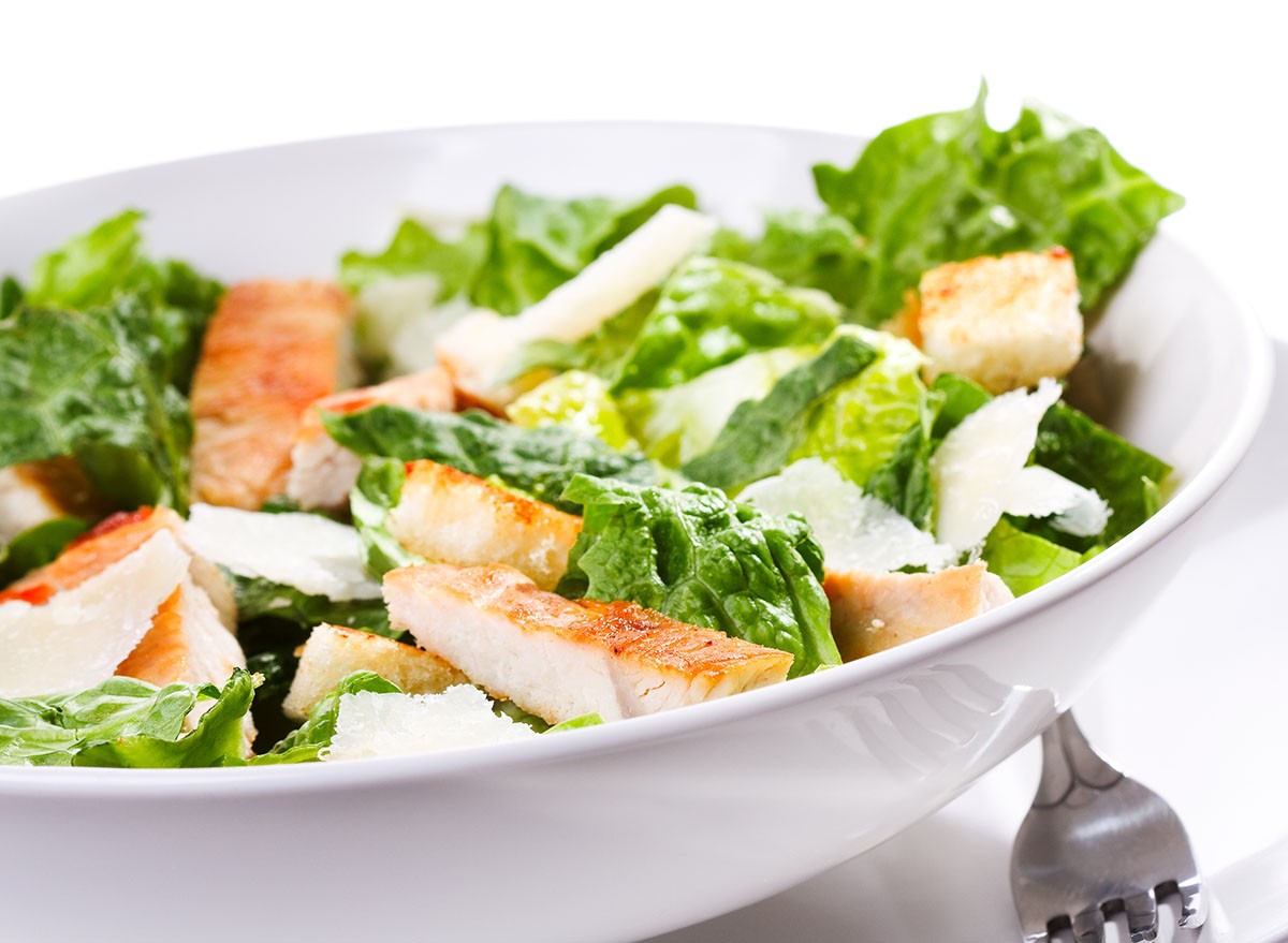 Caesar salad with chicken and greens on white background