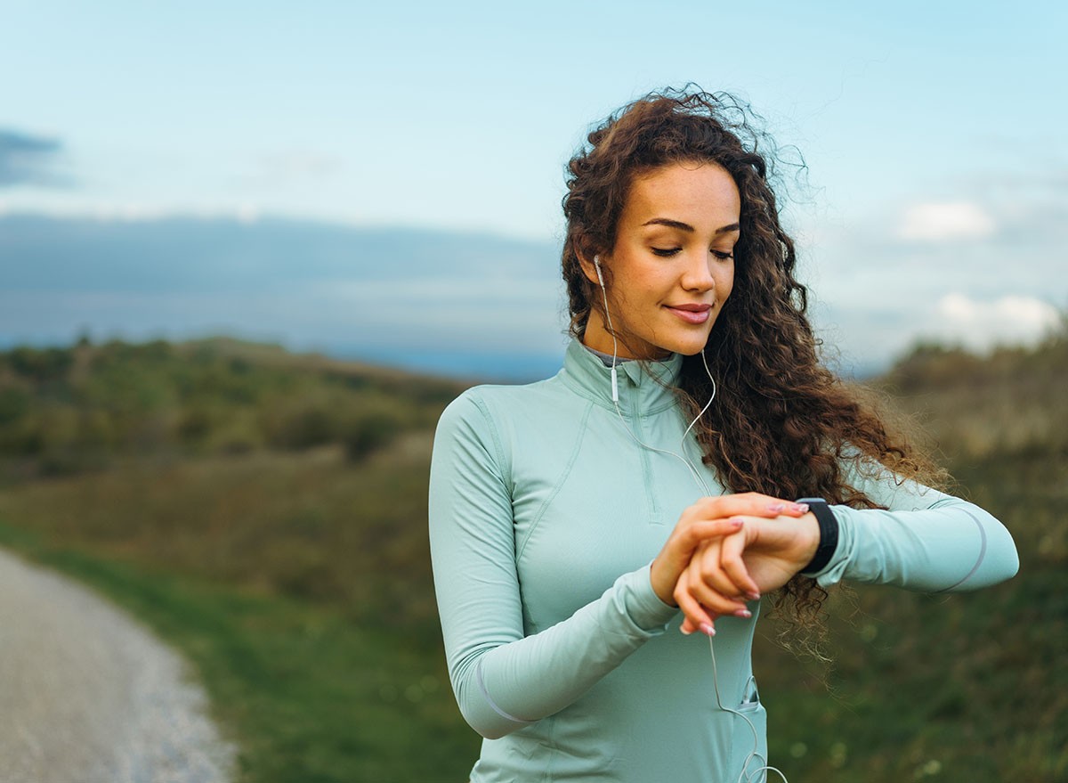 A fitness girl is looking at her smart watch to see how many steps she has been taking, as well as her pulse rate.