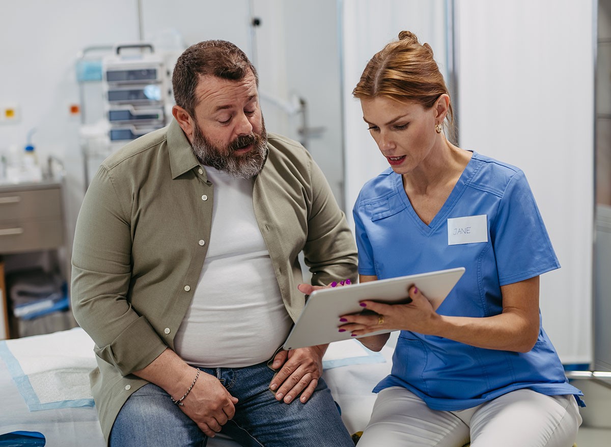 Female doctor consulting with overweight patient, discussing test result in doctor office. Obesity affecting middle-aged men's health. Concept of health risks of overwight and obesity.