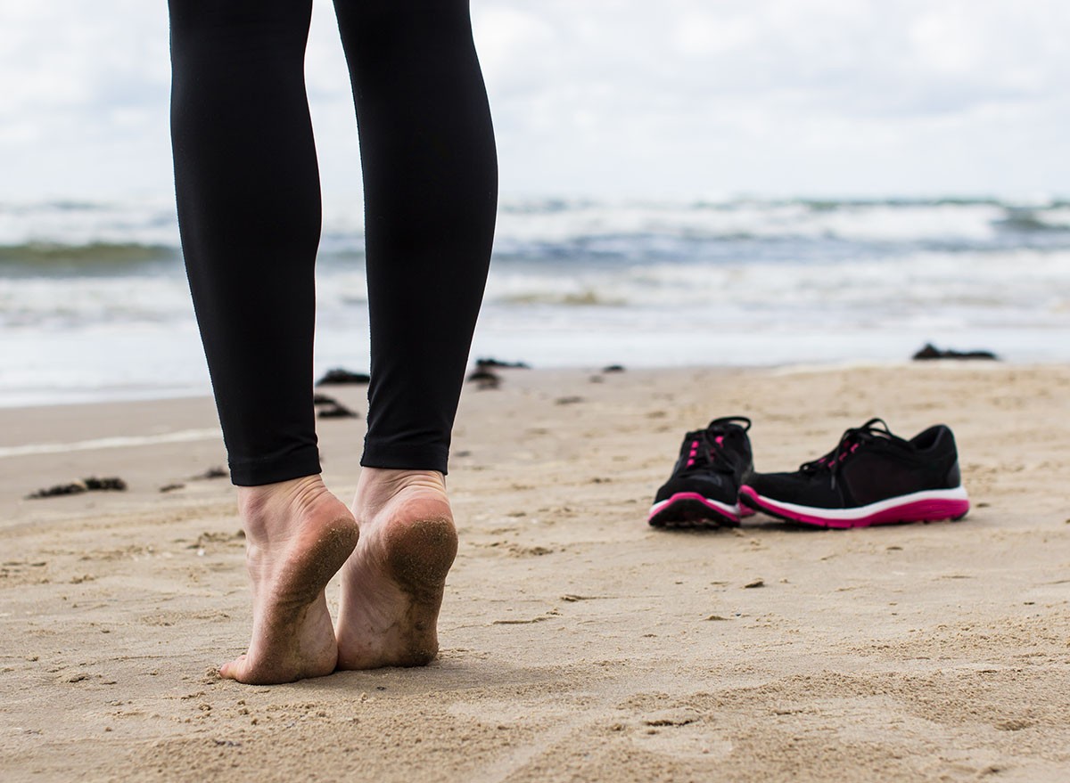 Close-up of gil's bare feet on wet sand. Running shoes and cold sea in the background. tip toe, Calf raises