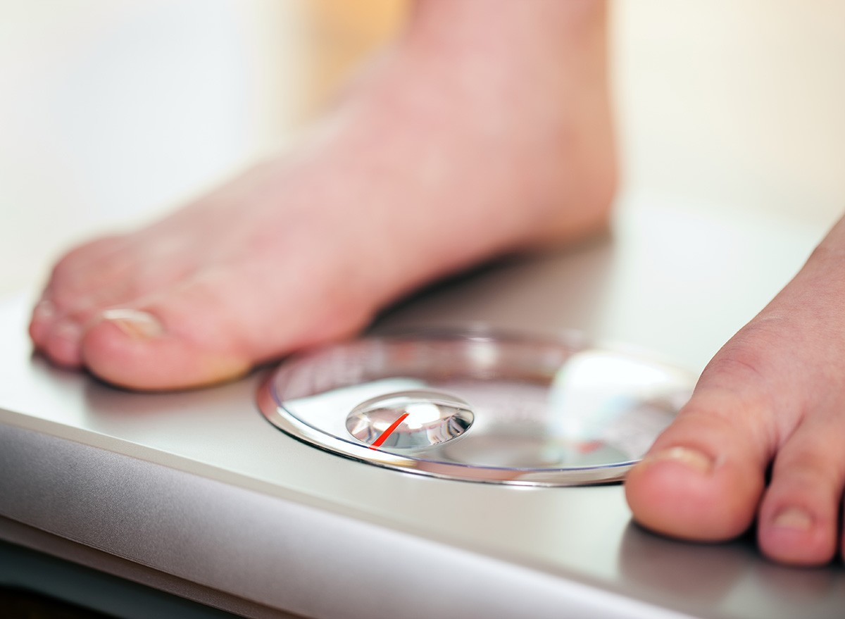 Woman (only feet to be seen) standing on bathroom scale measuring her weight controlling her dieting results